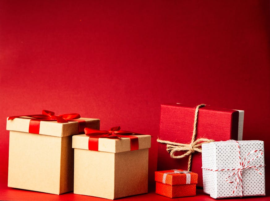 A collection of colorful gift boxes with ribbons on a rich red background, perfect for holiday themes.